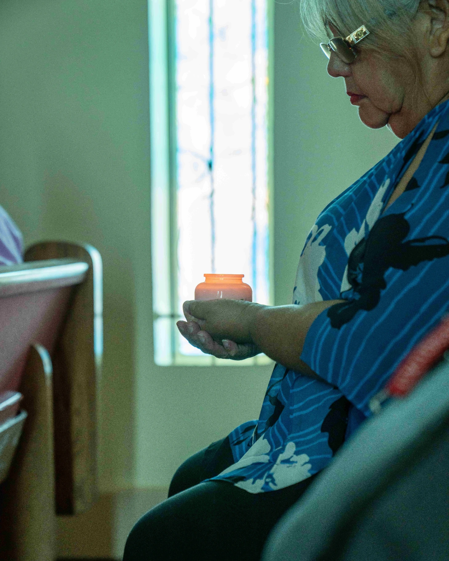 Woman holding a memorial candle by sunlit window
